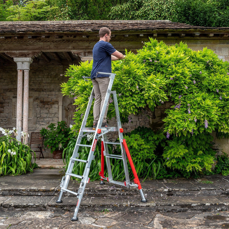 A person using a garden platform to trim a shrub