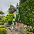 A person standing on a fully extended All Terrain Platform to trim a hedge