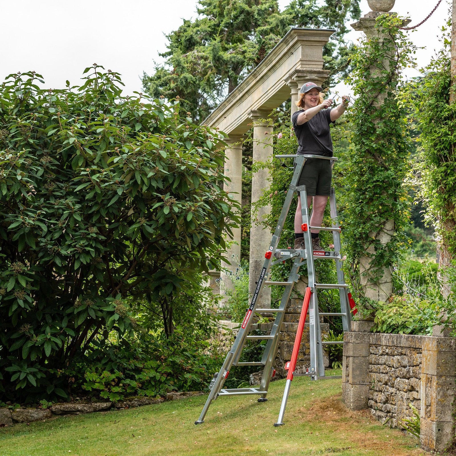 A person trimming a tree while standing on the All Terrain Telescopic Platform