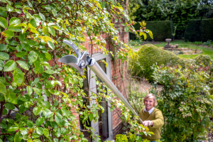 Garden tools maintenance: A lady using long-reach pruners to cut a branches 